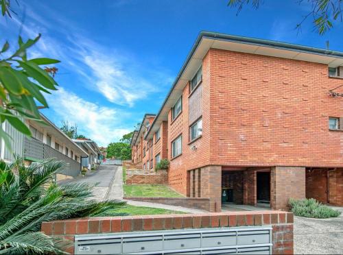 a red brick building with a street in front of it at 2 Bed Bar Beach Apartment - stroll to beach & cafes, supermarket apartment number 6 in Newcastle