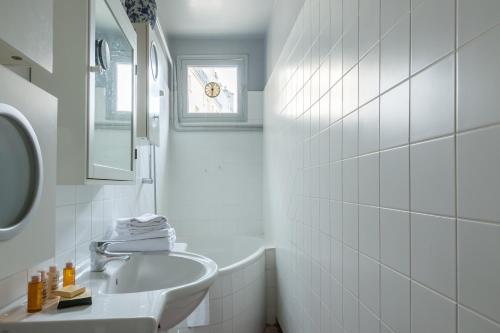 une salle de bain blanche avec un lavabo et un miroir dans l'établissement Veeve - Muted Beauty in Batignolles, à Paris