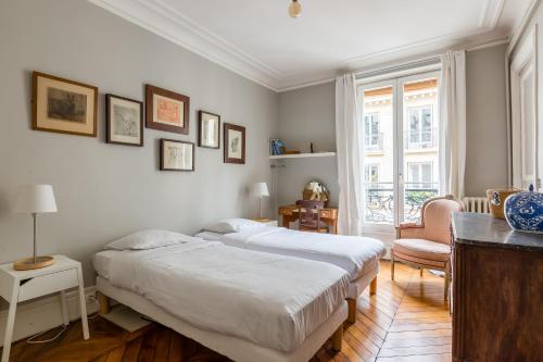 a bedroom with two beds and a chair at Veeve - Muted Beauty in Batignolles in Paris