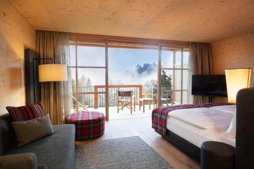 Habitación de hotel con cama y balcón en ADLER Lodge RITTEN en Soprabolzano