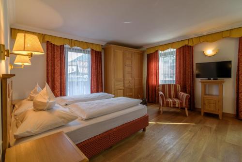 a bedroom with a large bed and a television at Hotel Gasthof Zum Mohren in Tesimo