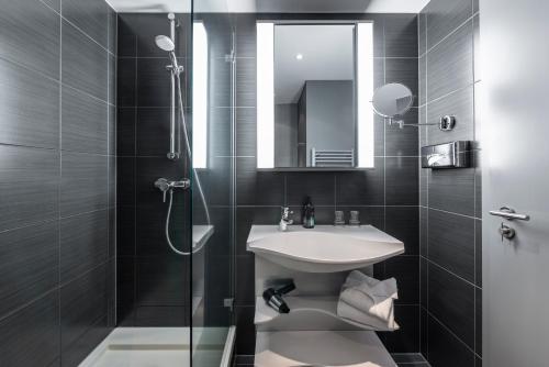 a bathroom with a sink and a shower with a mirror at Aparthotel Adagio Berlin Kurfürstendamm in Berlin