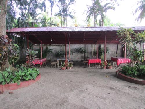 a pavilion with red tables and chairs and palm trees at Felipa Beach and Guesthouse - Lotus in Dumaguete