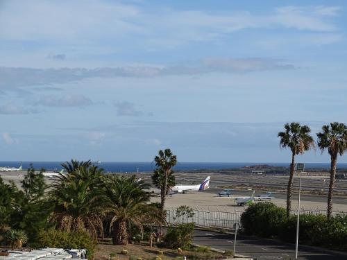 an airport with palm trees and planes on the runway at Rickaty Lodge Bed and Breakfast, Airport Hotel, Hotel de aeropuerto, Las Palmas Airport, Gran Canaria Airport, LPA, Spain in Las Puntillas