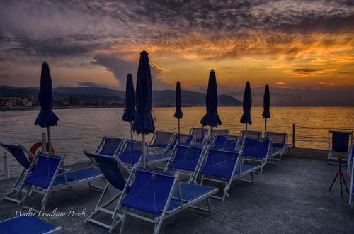 a group of chairs and umbrellas on a pier with the water at Casa Gemma in Diano Marina