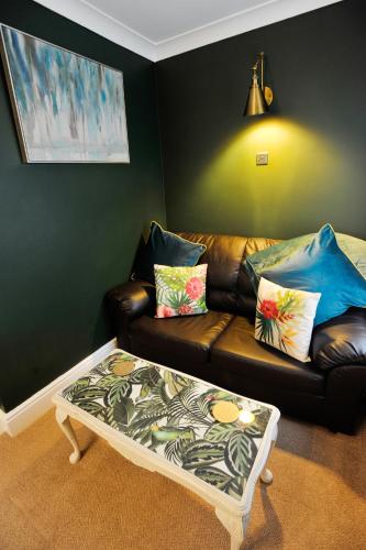 a living room with a leather couch and a coffee table at The Cleveland in Torquay