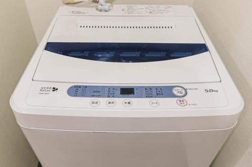 a white washing machine sitting next to a wall at TKD HOUSE Asahikawa in Asahikawa