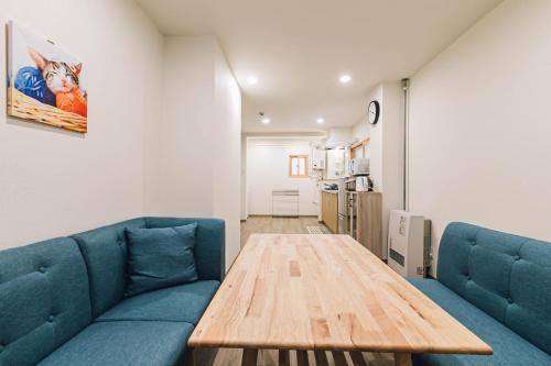a living room with a blue couch and a wooden table at TKD HOUSE Asahikawa in Asahikawa