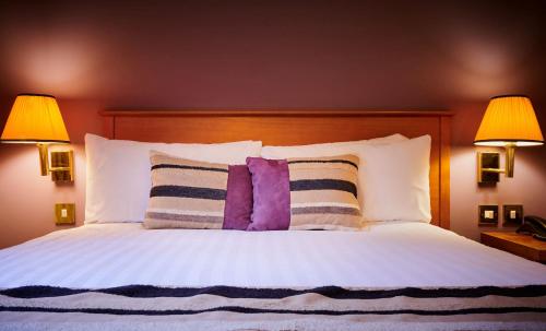 a bedroom with a bed with pillows and two lamps at Stirling Court Hotel in Stirling