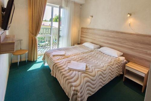 um quarto de hotel com uma cama grande e uma janela em Vėjo Burė em Palanga