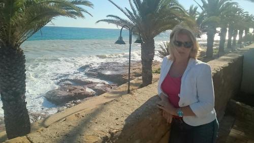 a woman standing next to a wall next to the ocean at Beach front/waterside apartment in Luz