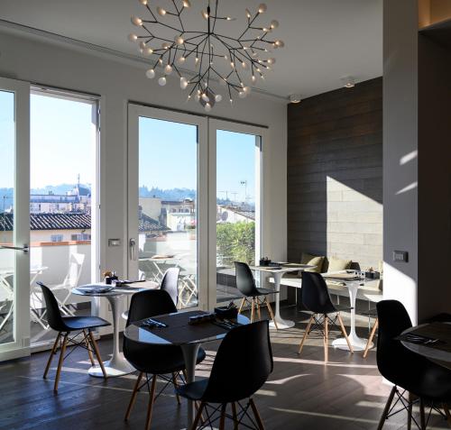 Un restaurante con mesas y sillas y grandes ventanales. en B&B The Attico, en Florencia