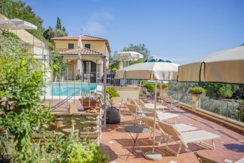a patio with chairs and umbrellas next to a pool at Villa Denise in Campiglia Marittima