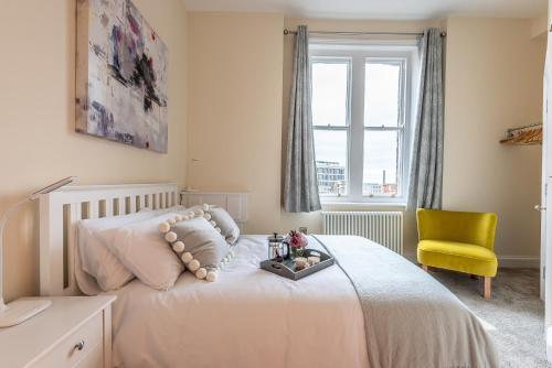 a bedroom with a white bed and a yellow chair at Newly Converted Apartment Rowntree House Shambles in York