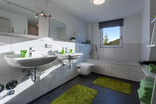 a bathroom with two sinks and a toilet and a window at Ferienwohnungen Schwabenhof in Schramberg