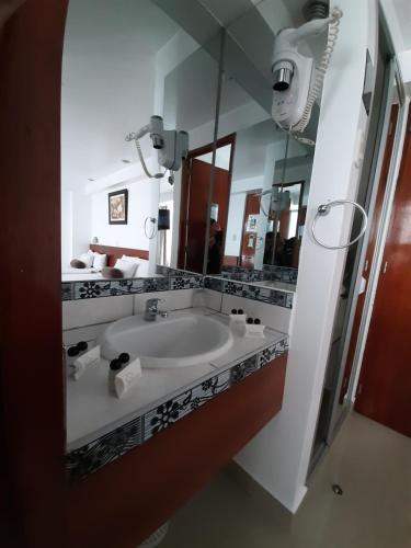 a bathroom with a sink and a large mirror at Flower's House MachuPicchu in Machu Picchu