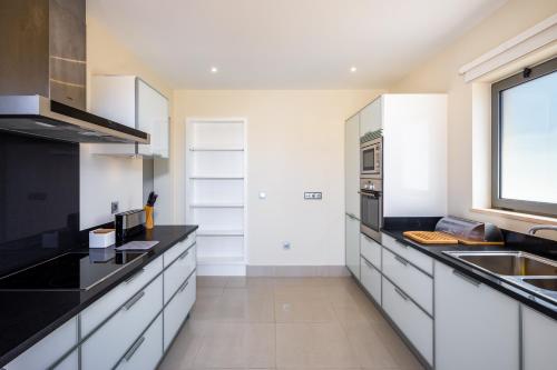 a kitchen with white cabinets and black counter tops at Shantiapartments in Vilamoura
