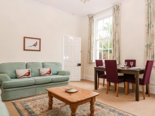 a living room with a green couch and a table at Blundell's Cottage in Broadway