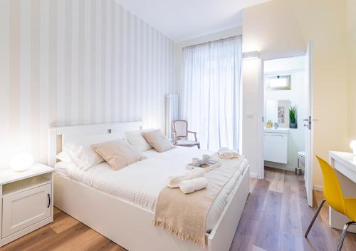 ein weißes Schlafzimmer mit einem großen weißen Bett und einem Schreibtisch in der Unterkunft CITy TURIN HUB in Turin