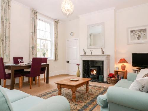a living room with a table and a fireplace at Blundell's Cottage in Broadway