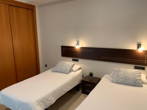 two beds in a room with lights on the wall at Apartamentos Arosa in Isla de Arosa