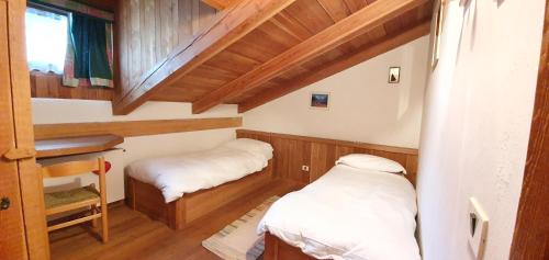 two beds in a small room with wooden walls at Rustico nelle Dolomiti in Val di Zoldo