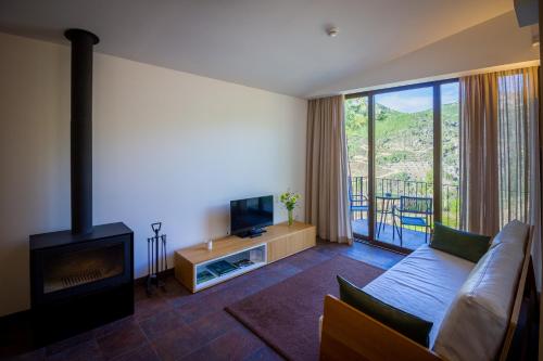 a living room with a couch and a fireplace at Casas do Almourão in Foz do Cobrão