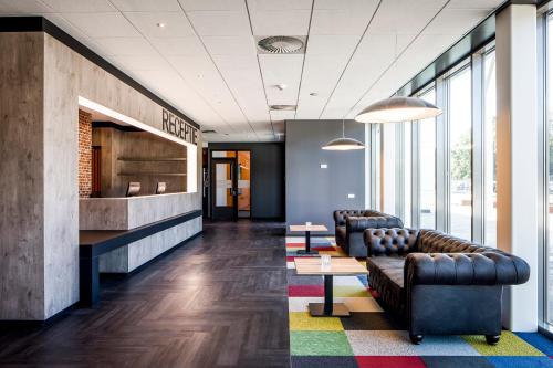 a lobby with couches and tables in a building at Fletcher Hotel-Restaurant Oss in Oss