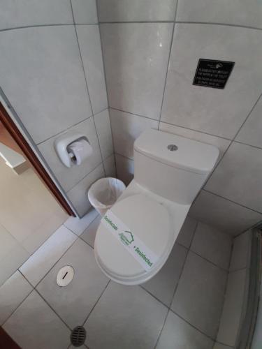 a bathroom with a toilet with a sign on it at Flower's House MachuPicchu in Machu Picchu