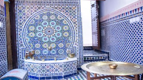 a bathroom with a tub and a tile wall at Riad Dar Senhaji in Fez