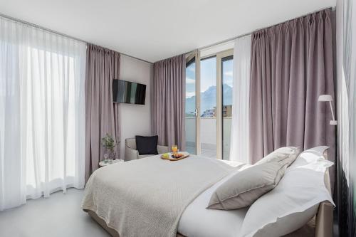 a white bedroom with a bed and a window at VISIONAPARTMENTS Neustadtstrasse - contactless check-in in Luzern