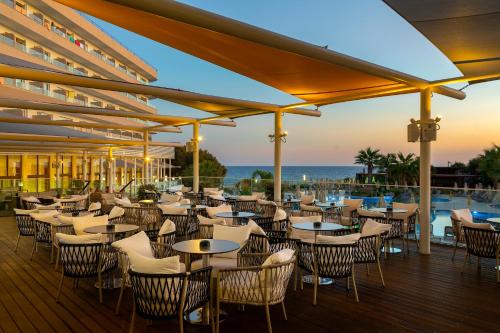 a restaurant with tables and chairs on a deck at Melissi Beach Hotel & Spa in Ayia Napa
