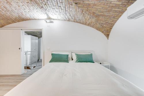 una camera da letto con un letto bianco con cuscini verdi di Rome Boutique Home Colosseum a Roma