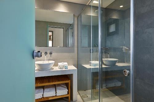 a bathroom with two sinks and a glass shower at Castello Village Resort in Sisi