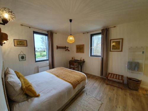 a bedroom with a large bed and two windows at "Au jardin sur l'eau" Hortillonnages in Amiens