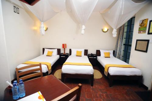 a room with three beds and a table and a dining room at Kenya Comfort Hotel in Nairobi