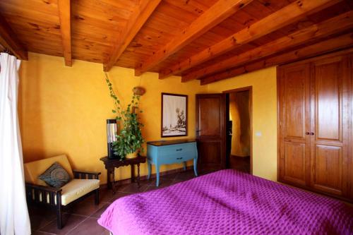 a bedroom with a purple bed and a wooden ceiling at Casa Roco 2 in Tías