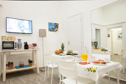 una sala da pranzo con sedie bianche e un tavolo con cibo di B&B Martucci Avenue a Napoli