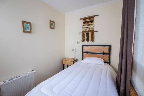 a bedroom with a large white bed in a room at Huellas y Senderos Hotel in Coihaique