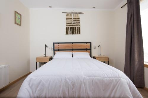 a bedroom with a large white bed with two night stands at Huellas y Senderos Hotel in Coihaique
