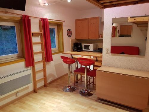 uma pequena cozinha com bancos vermelhos numa pequena casa em STUDIO CHALEUREUX aux pieds des pistes de ski des Glovettes em Villard-de-Lans