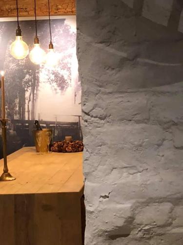 a stone wall in a room with a table and lights at B&B Langeveldemolen in Merchtem