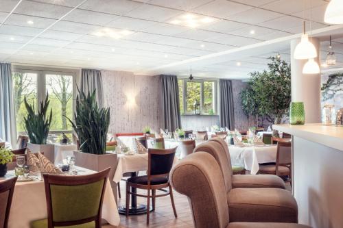 a restaurant with white tables and chairs and windows at Golfhotel Fahrenbach in Tröstau
