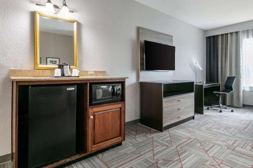 ein Hotelzimmer mit einem TV und einem Schreibtisch mit einer Mikrowelle in der Unterkunft Clarion Pointe Columbus-Bradley Park in Columbus