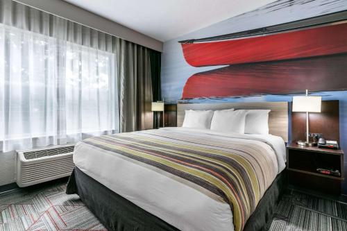 a hotel room with a bed with a painting on the wall at Clarion Pointe Columbus-Bradley Park in Columbus