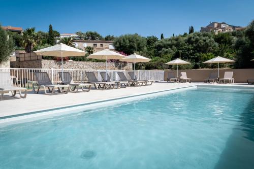 a swimming pool with chairs and umbrellas at Domaine A Marella in LʼÎle-Rousse