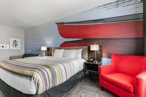 a hotel room with a bed and a red chair at Clarion Pointe Columbus-Bradley Park in Columbus