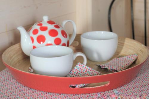 a red tray with two cups and a tea pot at LE PETIT NID DANS LA ROULOTTE in Roscanvel
