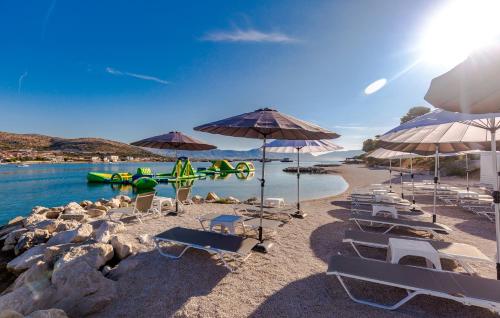a beach with chairs and umbrellas and the water at Hotel Brown Beach House & Spa in Trogir