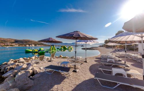a beach area with chairs and umbrellas at Hotel Brown Beach House & Spa in Trogir
